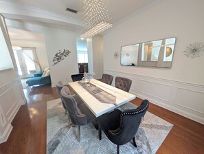 A dining area with a long table, six chairs, and a chandelier. - Monterey Bay Retreat | Private Pool + Gated (Jacksonville)