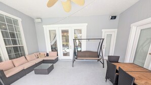 En möblerad uteplats med ett tak, en modulsoffa, en gunga och ett matbord med stolar.