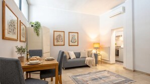 En moderne stue med spisebord, grå sofa og en lampe.