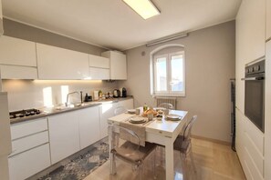 A modern kitchen with white cabinets, a dining table set for four, and a built-in oven. - 3-Bedroom Luxury Residence with 4 Beds & 2 Bathrooms in Bari (Bari)