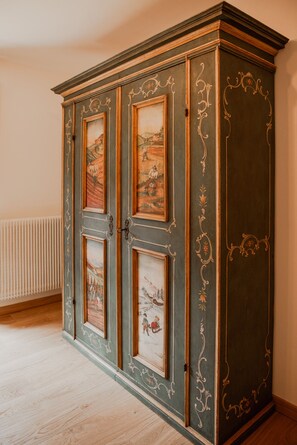 A large cabinet with ornate carvings and multiple doors, each with a framed painting. - Dimora del Cervo | Luxury Dolomites Retreat. Spectacular mountain view (Falcade)