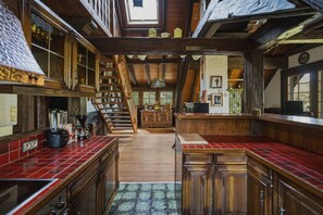Een ruime keuken met houten kastjes, een backsplash van rode tegels en een centraal eiland.