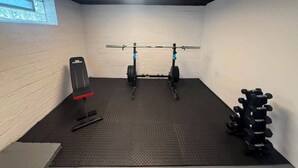 A gym with a pull-up bar, weight bench, and a rack of dumbbells. - Spacious house in University heights (University Heights)