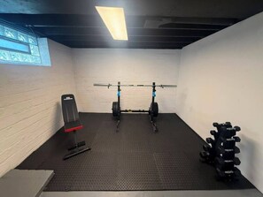 Ein Fitnessraum mit Klimmzugstange, Gewichtbank und einer Hantelbank.