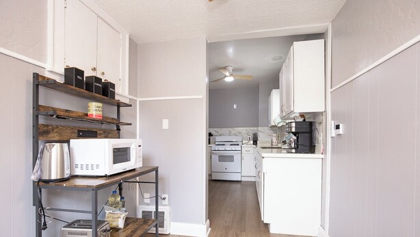 A compact kitchen with white cabinets, a microwave, a toaster, and a coffee maker on a shelf. - Spacious house in University heights (University Heights)