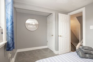 Ein Schlafzimmer mit einem Bett, einer Tür, einem Spiegel und einer Treppe.