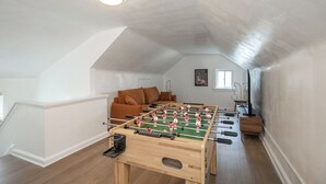 A room with a foosball table, a sofa, and a window. - Spacious house in University heights (University Heights)