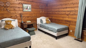 A room with two beds, a desk, a chair, a teddy bear, and a ceiling fan.