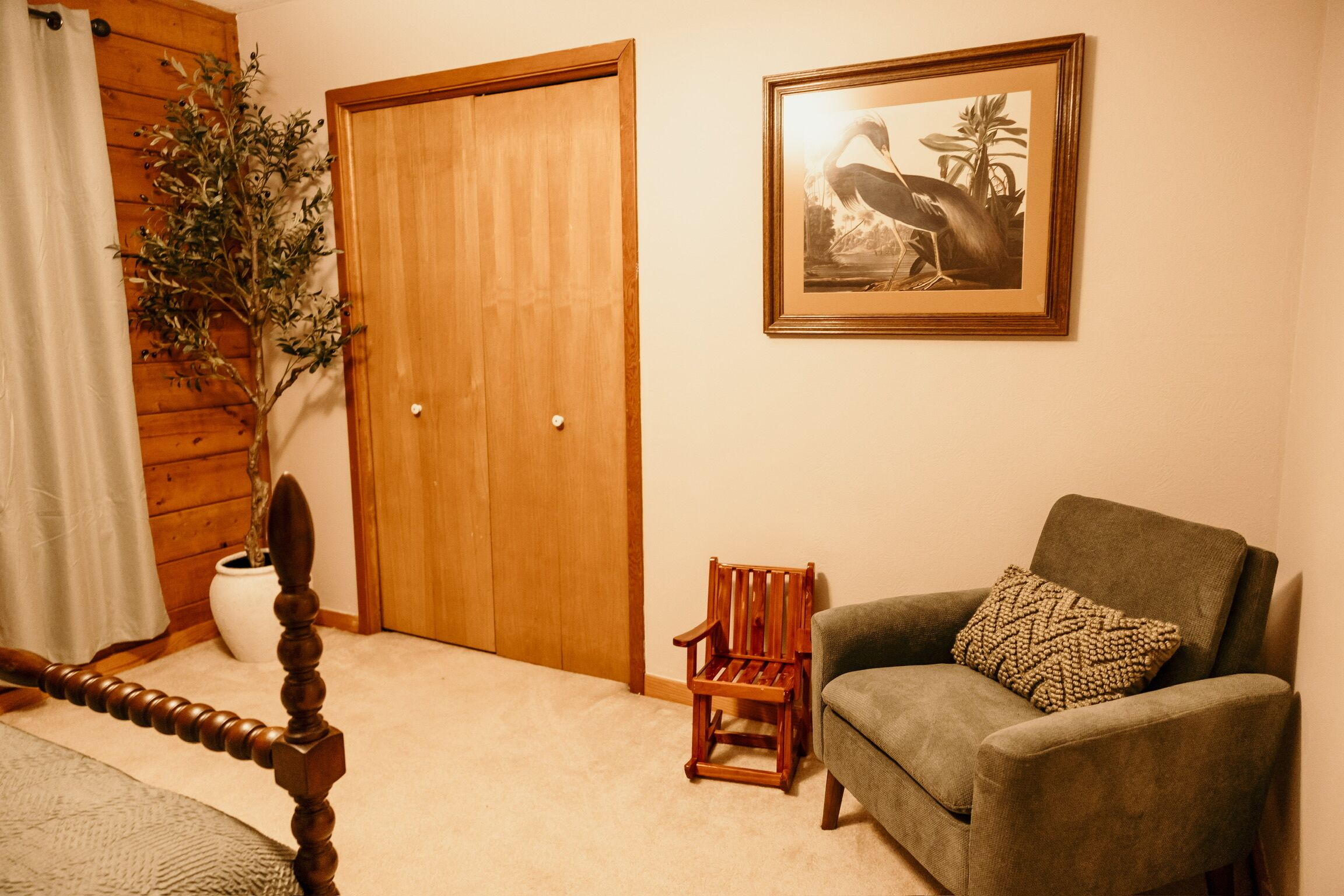 Une pièce avec une porte en bois, un tableau encadré au mur, une chaise en bois et une petite table.