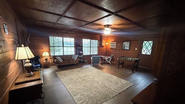 A cozy room with a wooden ceiling, a sofa, a coffee table, and a rug. - Charming 3-bedroom cabin with AC on Lone Star Lake (Lone Star)