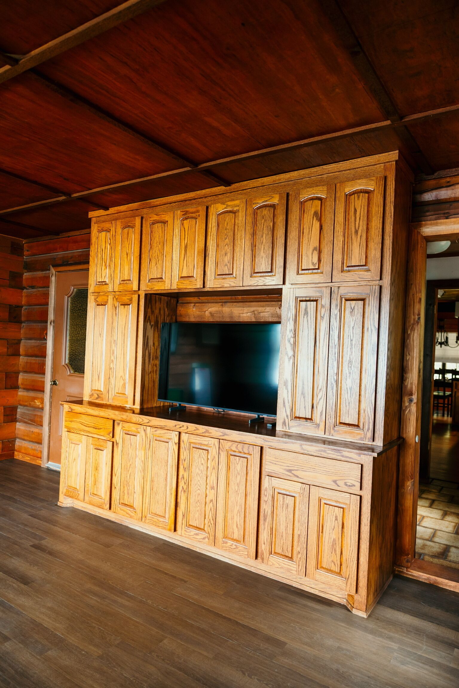 Een houten blokhut vanbinnen met een tv-meubel en een grote televisie.