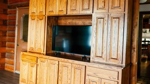 A log cabin interior with a wooden entertainment center and a large TV. - Charming 3-bedroom cabin with AC on Lone Star Lake (Lone Star)
