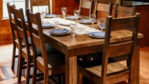 A wooden dining room with a chandelier, wooden chairs, and a table set for six. - Charming 3-bedroom cabin with AC on Lone Star Lake (Lone Star)