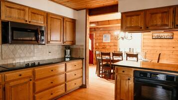 A kitchen with wooden cabinets, a microwave, a coffee maker, and a dining area with chairs and a table.