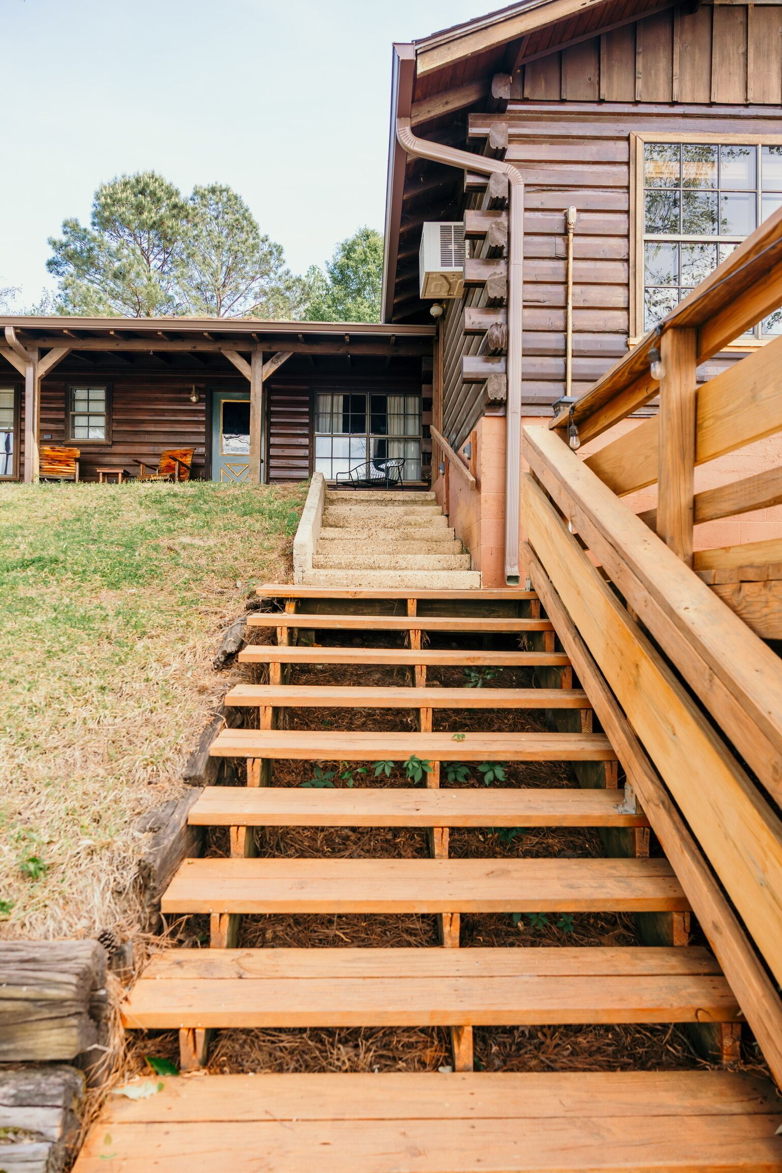 Een houten trap die leidt naar een chalet met een overdekte veranda en uitzicht op het omliggende landschap.