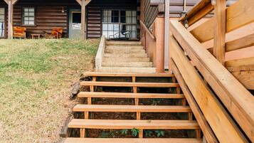 Een houten trap die leidt naar een chalet met een overdekte veranda en uitzicht op het omliggende landschap.