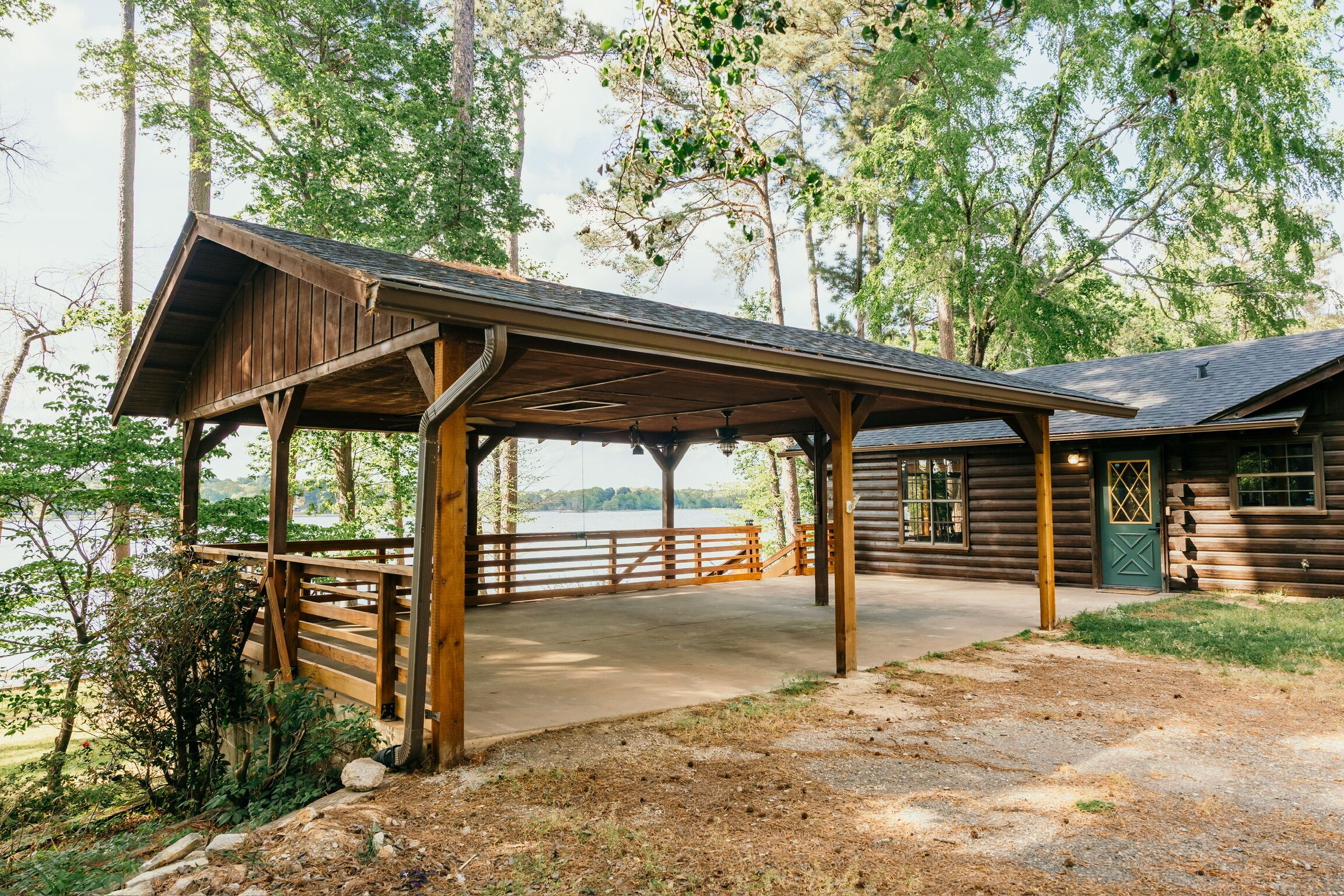 A wooden cabin with a covered porch overlooking a lake.