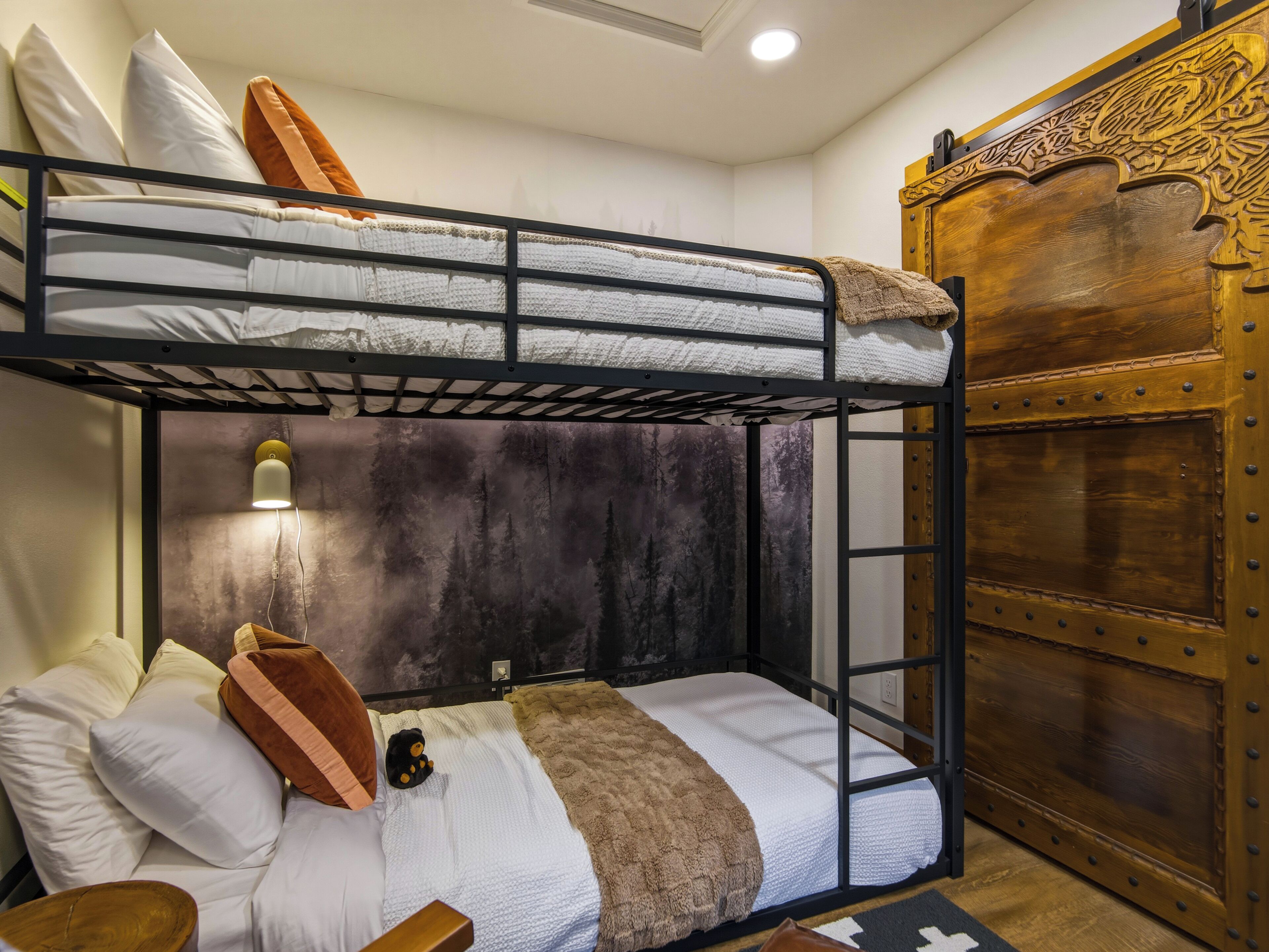 A bunk bed with a headboard, pillows, a blanket, and a small stuffed toy.