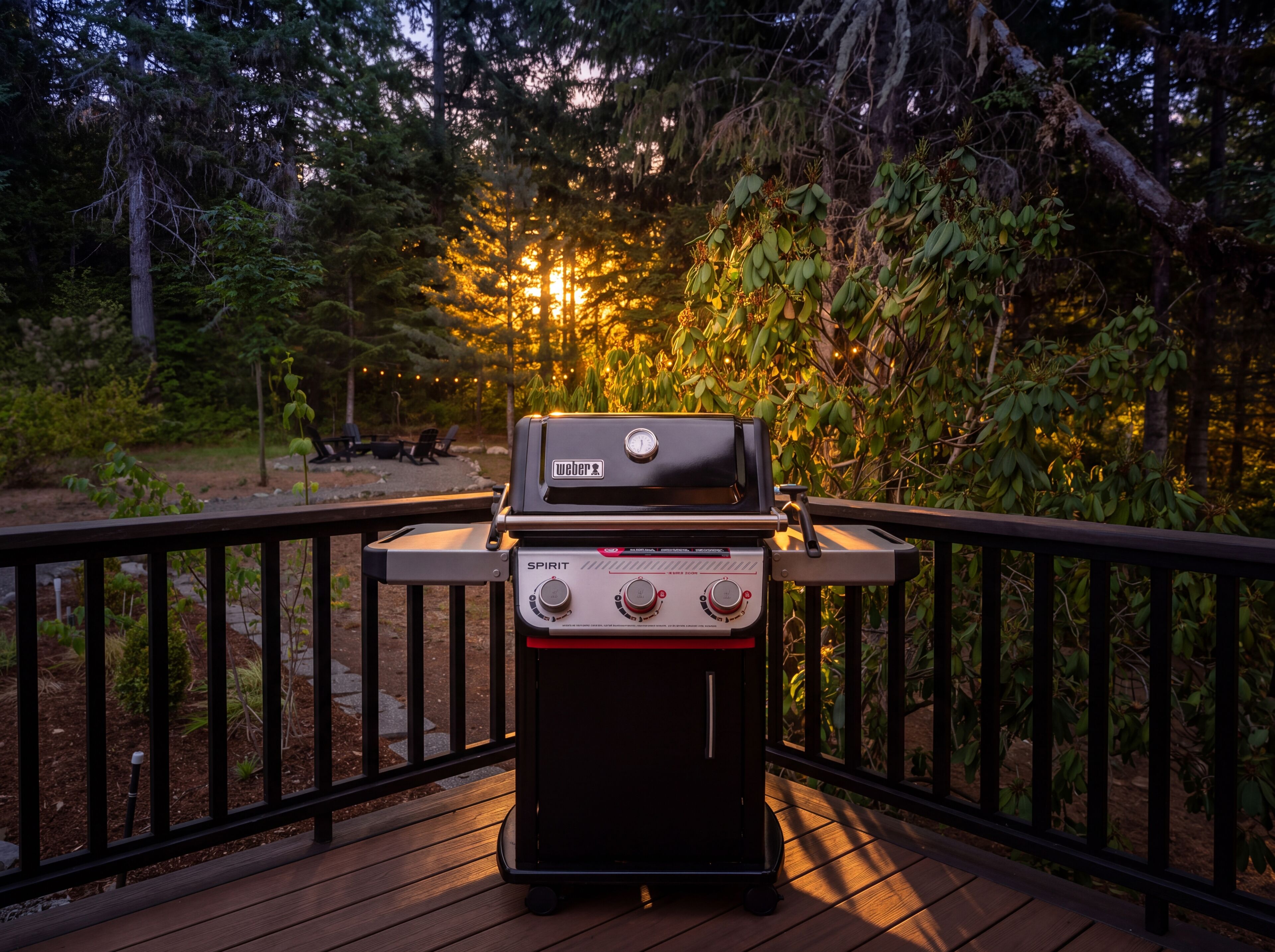 Un barbecue Weber Spirit sur une terrasse extérieure, avec vue sur une zone boisée.
