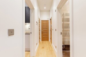 A hallway with a wooden door, a light switch, and a towel rack. - Super Central Lovely 1BR Flat - Fitzrovia (London)