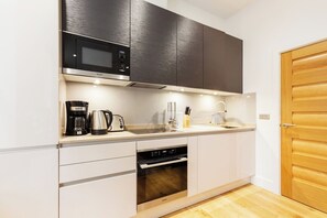 A compact kitchen with a microwave, coffee maker, toaster, sink, and oven. - Super Central Lovely 1BR Flat - Fitzrovia (London)