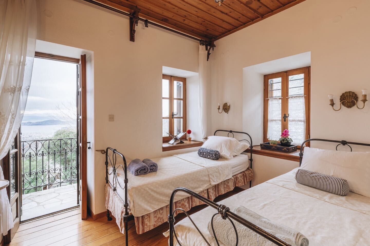 A bedroom with two beds, a balcony, and a view of the outdoors.