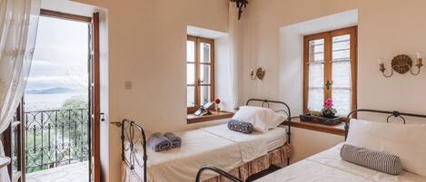 A bedroom with two beds, a balcony, and a view of the outdoors.