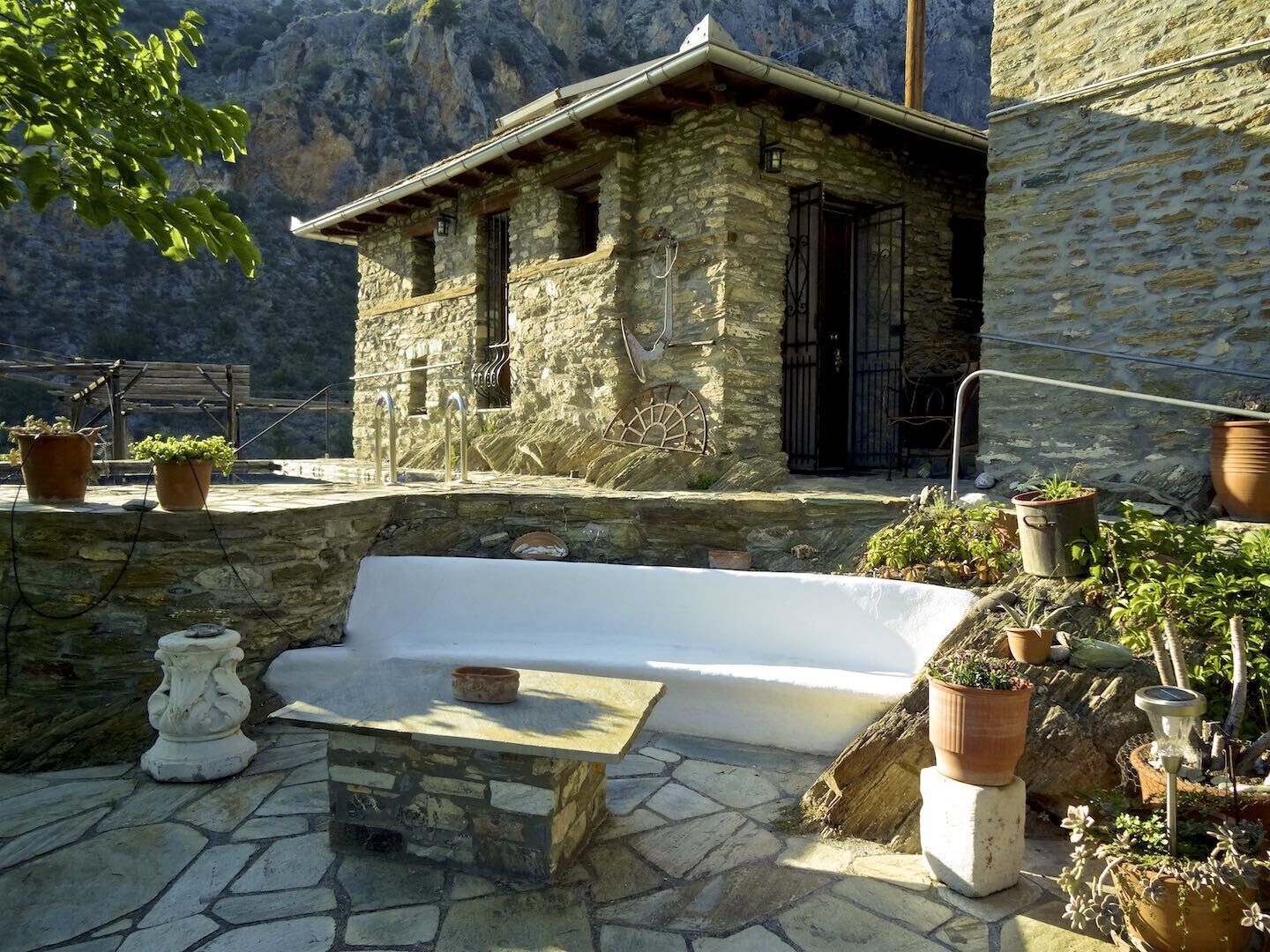 A stone building with a small porch and a stone bench.