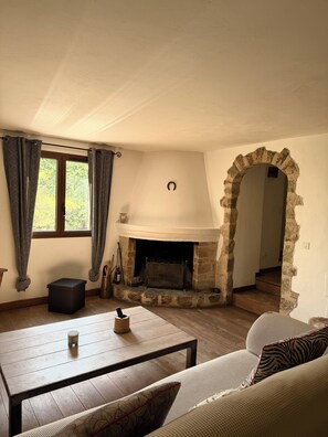 Ein Wohnzimmer mit Kamin, einer Couch, einem Couchtisch und einem Fenster mit Vorhängen.