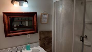 A bathroom with a wooden-framed mirror, a sink with three faucets, a towel, and a wall-mounted light fixture.