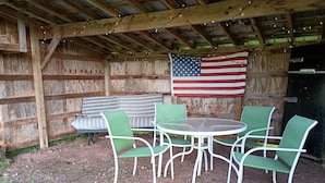 An outdoor seating area with a table and chairs, a wooden fence, and an American flag.