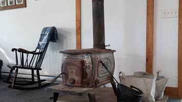 A rustic room with a wood-burning stove, a rocking chair, and a 'Welcome' sign on the wall.
