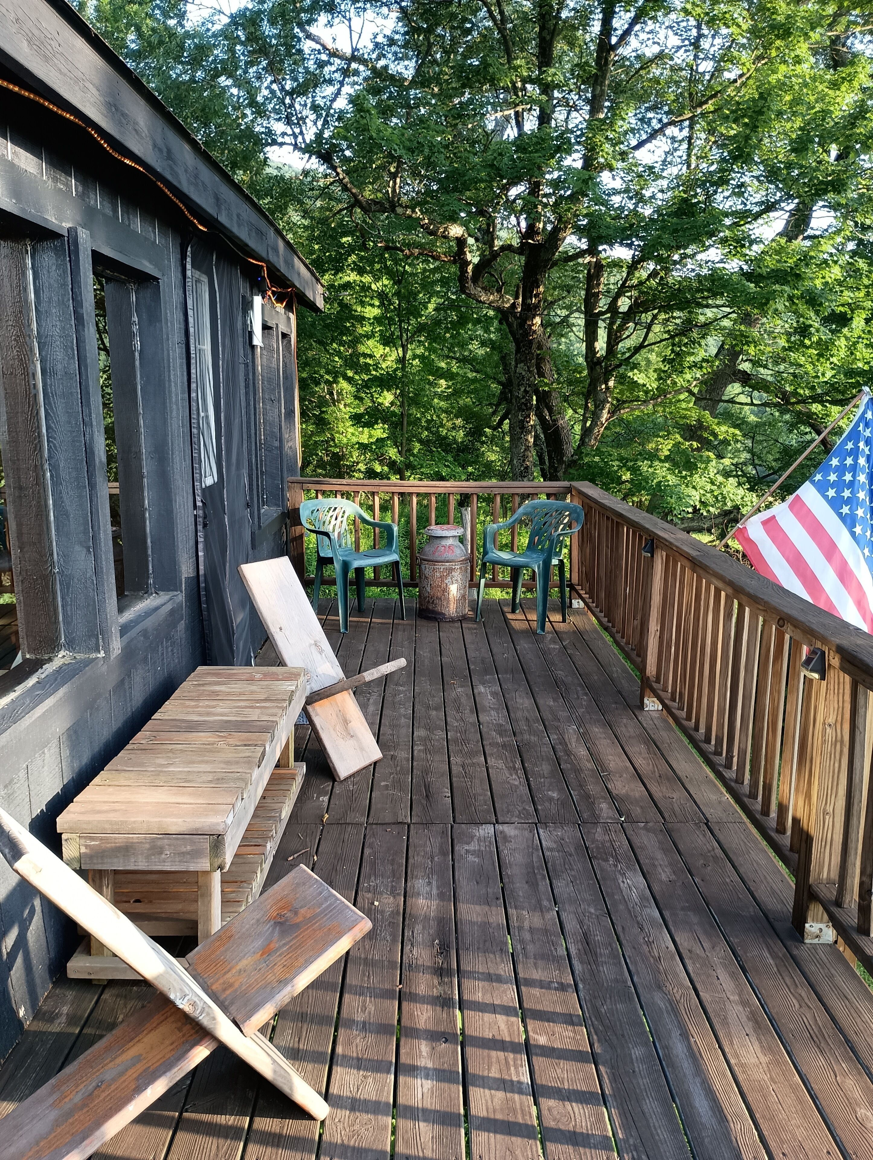 A wooden deck with a railing, a flag, and outdoor seating.