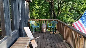 A wooden deck with a railing, a flag, and outdoor seating.