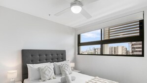 A bedroom with a bed, nightstand, lamp, and a window with blinds.