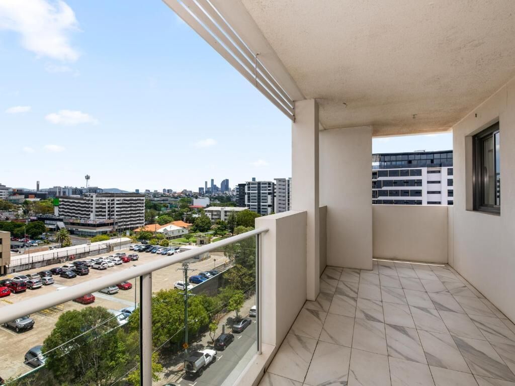 Un balcone con vista sulla città, un pavimento piastrellato e una ringhiera in vetro.