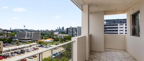 Un balcone con vista sulla città, un pavimento piastrellato e una ringhiera in vetro.