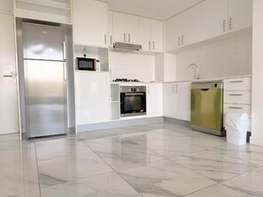 A modern kitchen with a stainless steel refrigerator, microwave, oven, and dishwasher.