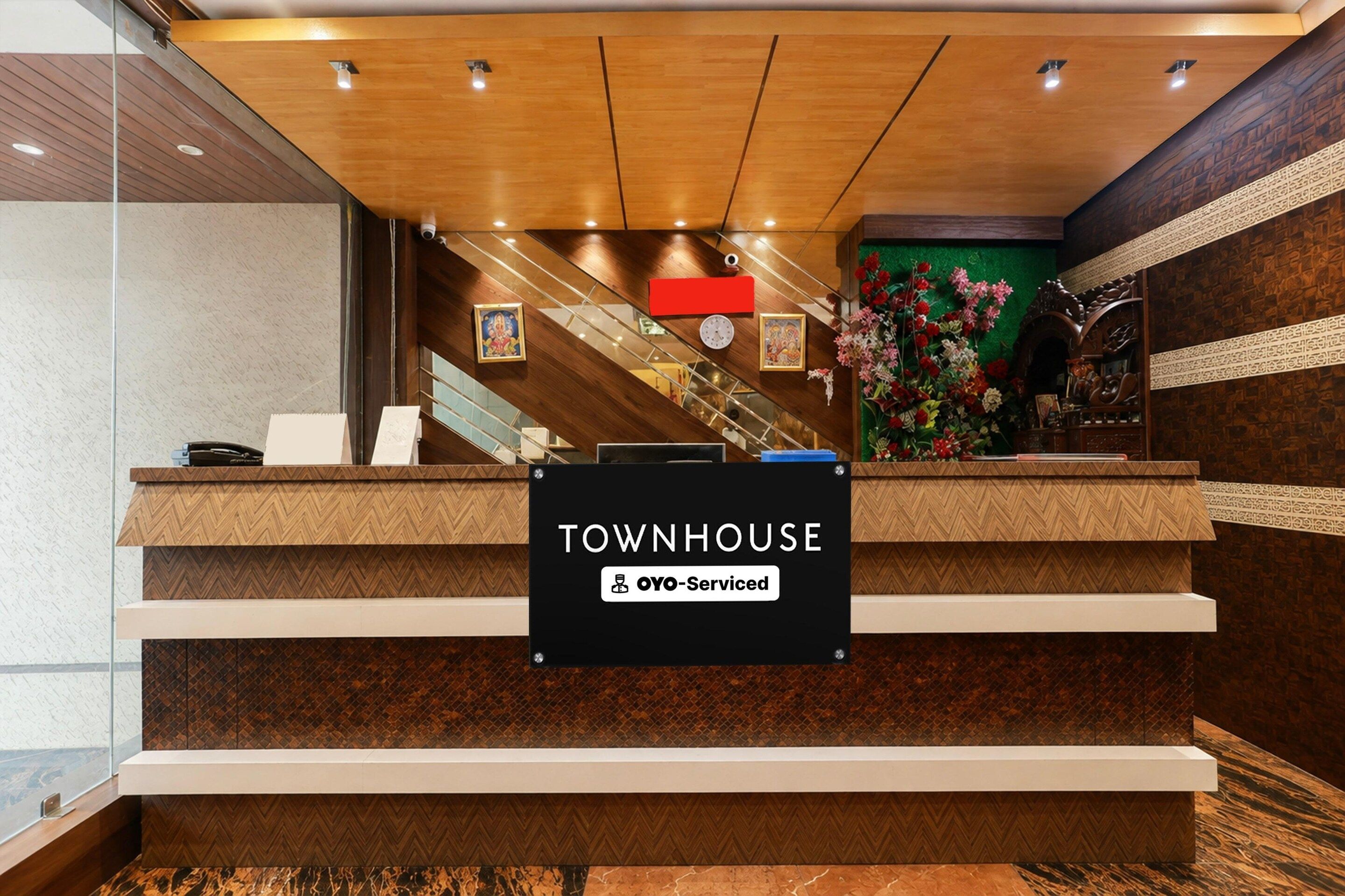 A reception desk with a sign indicating 'TOWNHOUSE' and 'oyO-Serviced' services.