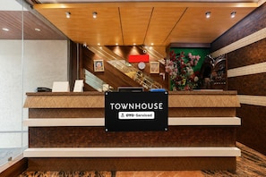 A reception desk with a sign indicating 'TOWNHOUSE' and 'oyO-Serviced' services.