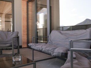 A modern outdoor seating area with a glass table and cushioned chairs. - Panoramic View Suite on the Kaunergrat (Kaunerberg)