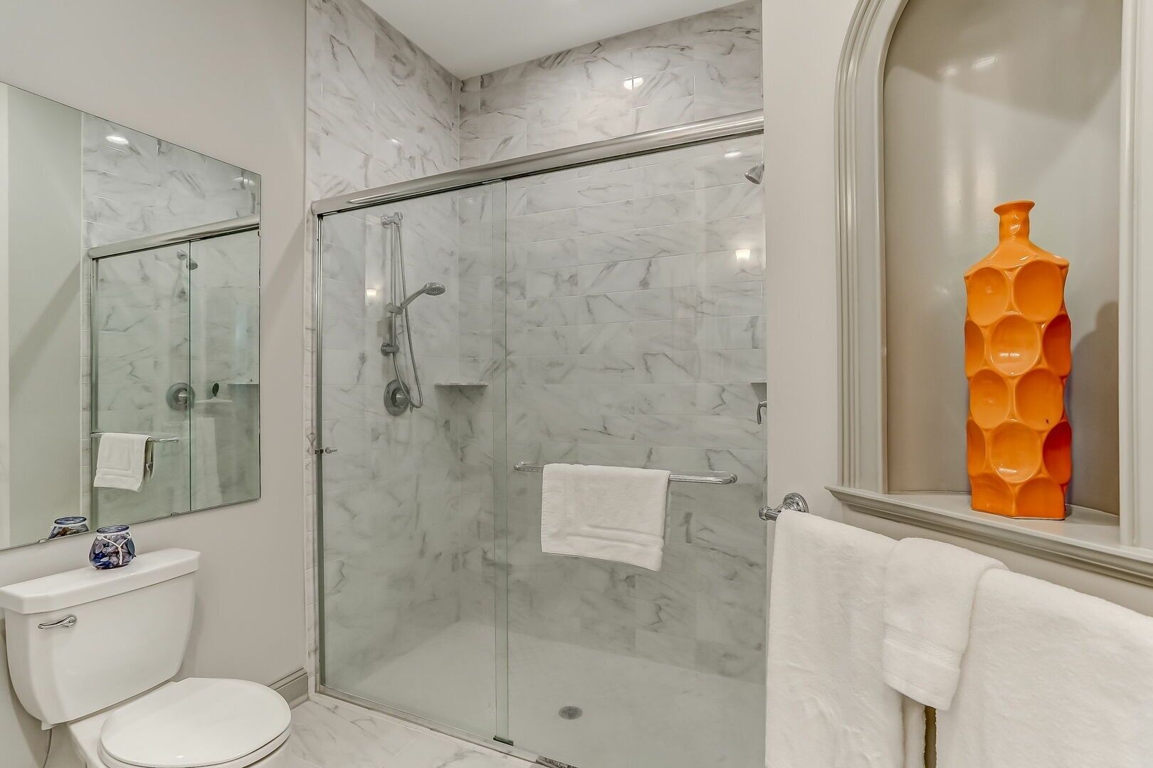 A modern bathroom with a glass-enclosed shower, a toilet, and a sink.