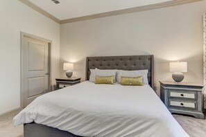 A bedroom with a large bed, two bedside tables, a door, and a light fixture on the ceiling. - Summerwoods 1504 2 Bedroom Condo (Fernandina Beach)