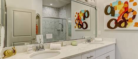 A modern bathroom with two sinks, a large mirror, and a shower.