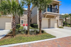 A residential building with a two-story structure, a balcony on the upper floor, and a driveway leading to a garage. - Summerwoods 1504 2 Bedroom Condo (Fernandina Beach)