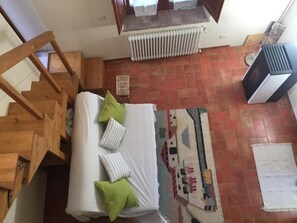 Une chambre à coucher avec un lit, un radiateur, une fenêtre et un escalier.