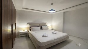 A bedroom with a large bed, bedside lamps, a wooden wardrobe, and a ceiling light fixture.