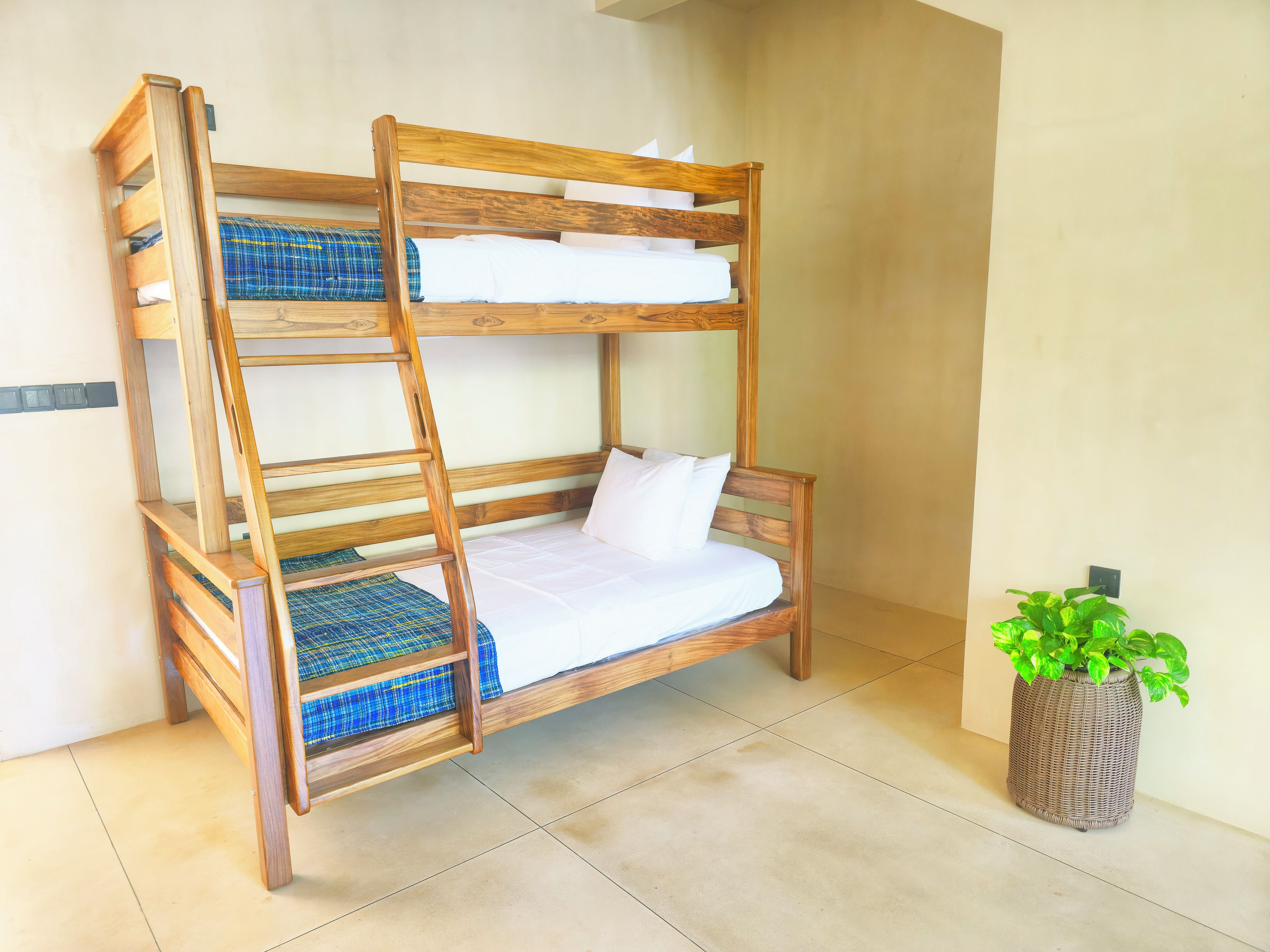 Una cama litera con escalera, una planta en maceta y suelo de baldosas.