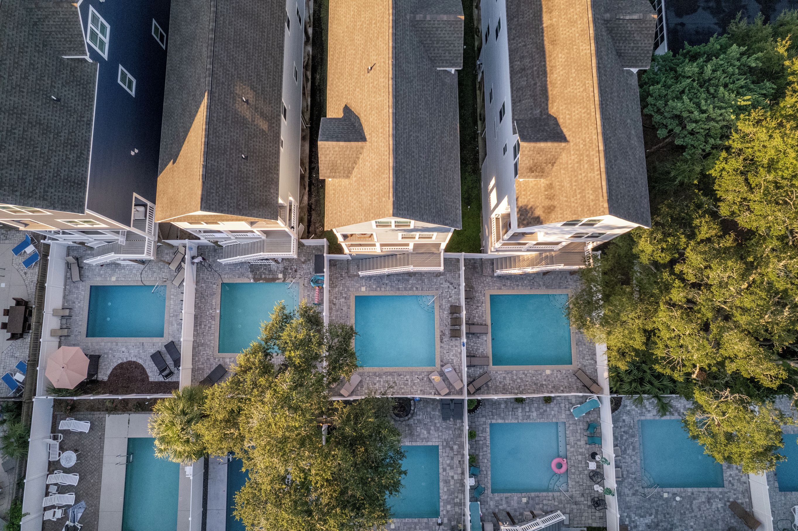 An aerial view of a hotel with multiple swimming pools, lounge areas, and a parking lot.