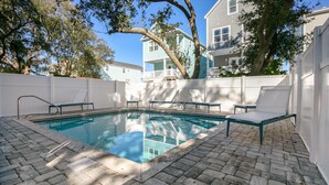 A swimming pool with a brick deck, surrounded by white fences and trees. - Coastal Daze: Pool & Short Walk to Beach (Surfside Beach)